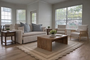 A living room with a sofa, two armchairs, a coffee table, and a rug. - Prestigious 1BR Escape w/ King + Queen, Pool & Gym (Plano)