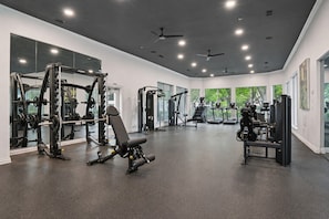 A gym with various exercise equipment, large windows, and ceiling fans. - Prestigious 1BR Escape w/ King + Queen, Pool & Gym (Plano)