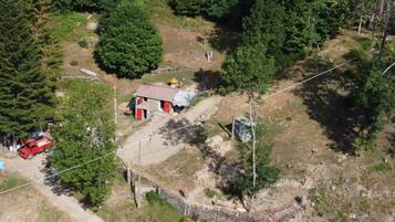 An aerial view of a rural area with a small building, a red vehicle, and a stone wall.