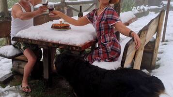A wooden table with snow on top, a bottle, and a plate with food.