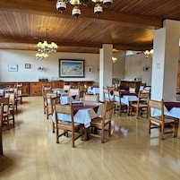 Un comedor con mesas y sillas de madera, candelabros y cuadros en las paredes.