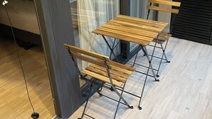 Una habitación con una mesa y sillas de madera, un panel de vidrio y vistas al exterior.