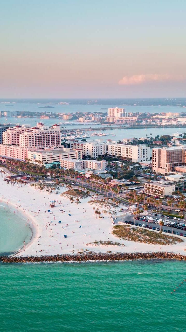 A coastal cityscape with a beachfront, hotels, and a marina.