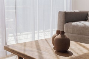 Ein Holztisch mit zwei Vasen, ein Sofa und Blick durch transparente Vorhänge.