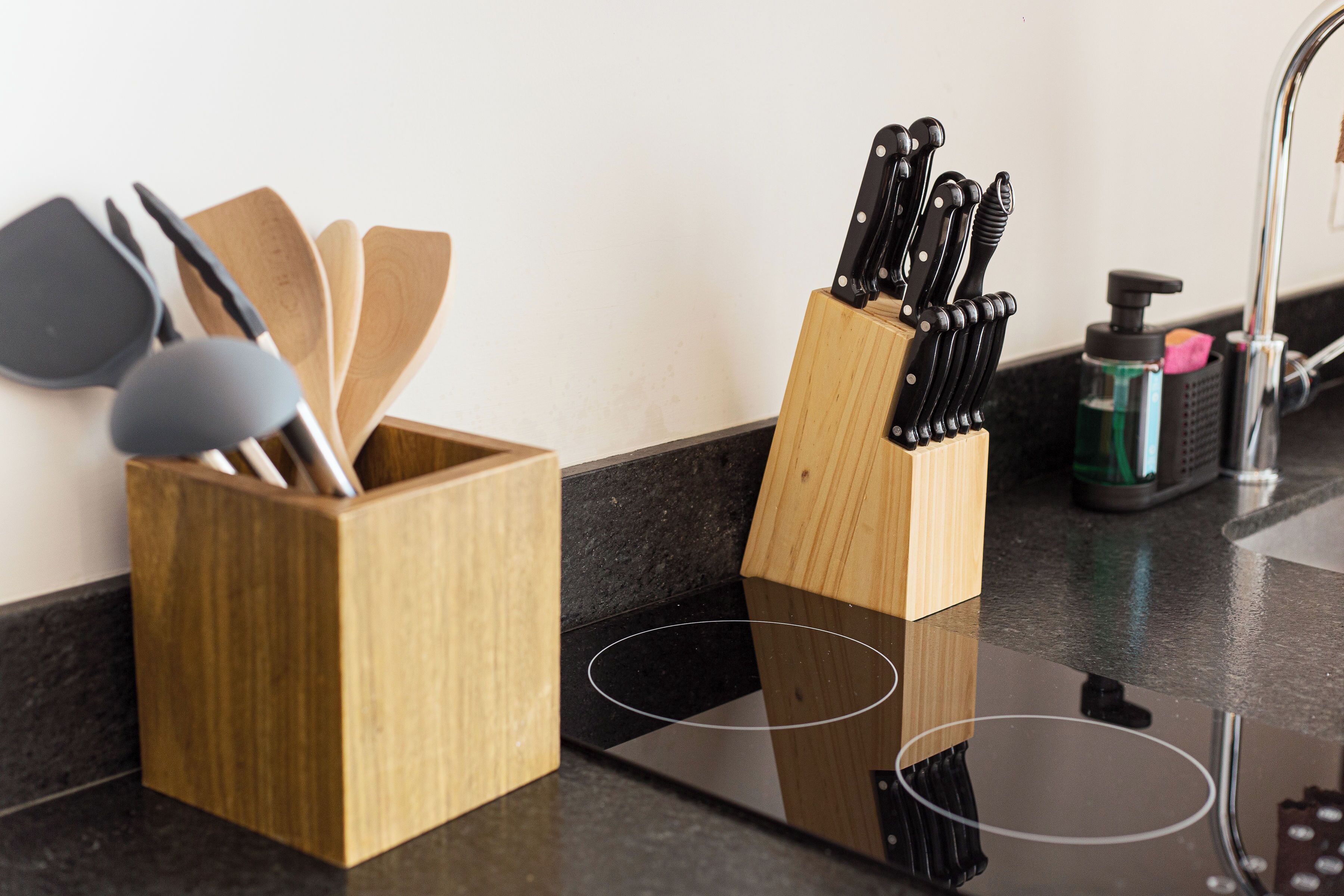 A kitchen counter with wooden utensil holders and a knife block.