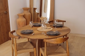 Ein runder Holztisch mit sechs Stühlen, einer Vase mit getrockneten Blumen und Weingläsern.