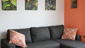 A dark grey sectional sofa with patterned cushions, a white wall, and three framed botanical paintings. - Bahamas Escape - Pool, Canal, Dockage, Beach (Freeport, Grand Bahama)