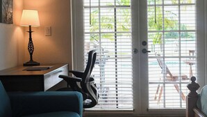 A room with a desk, chair, lamp, and a sliding glass door leading to an outdoor area with chairs and a table. - Bahamas Escape - Pool, Canal, Dockage, Beach (Freeport, Grand Bahama)