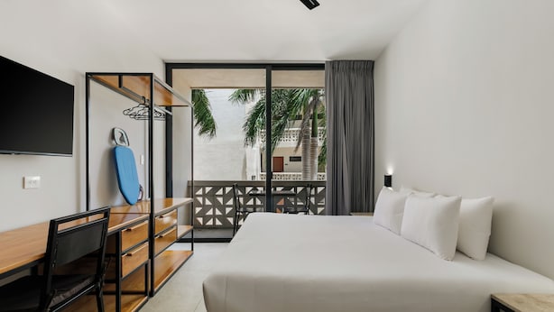 Una habitación de hotel con cama, escritorio, silla y televisor.