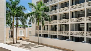 A modern building with multiple balconies, palm trees, and a clear sky.
