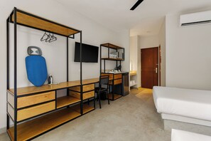 A compact room with a bed, a desk with a chair, a TV, and a shelf with items. - Villa Maria Teresa By Homirent (Mérida)