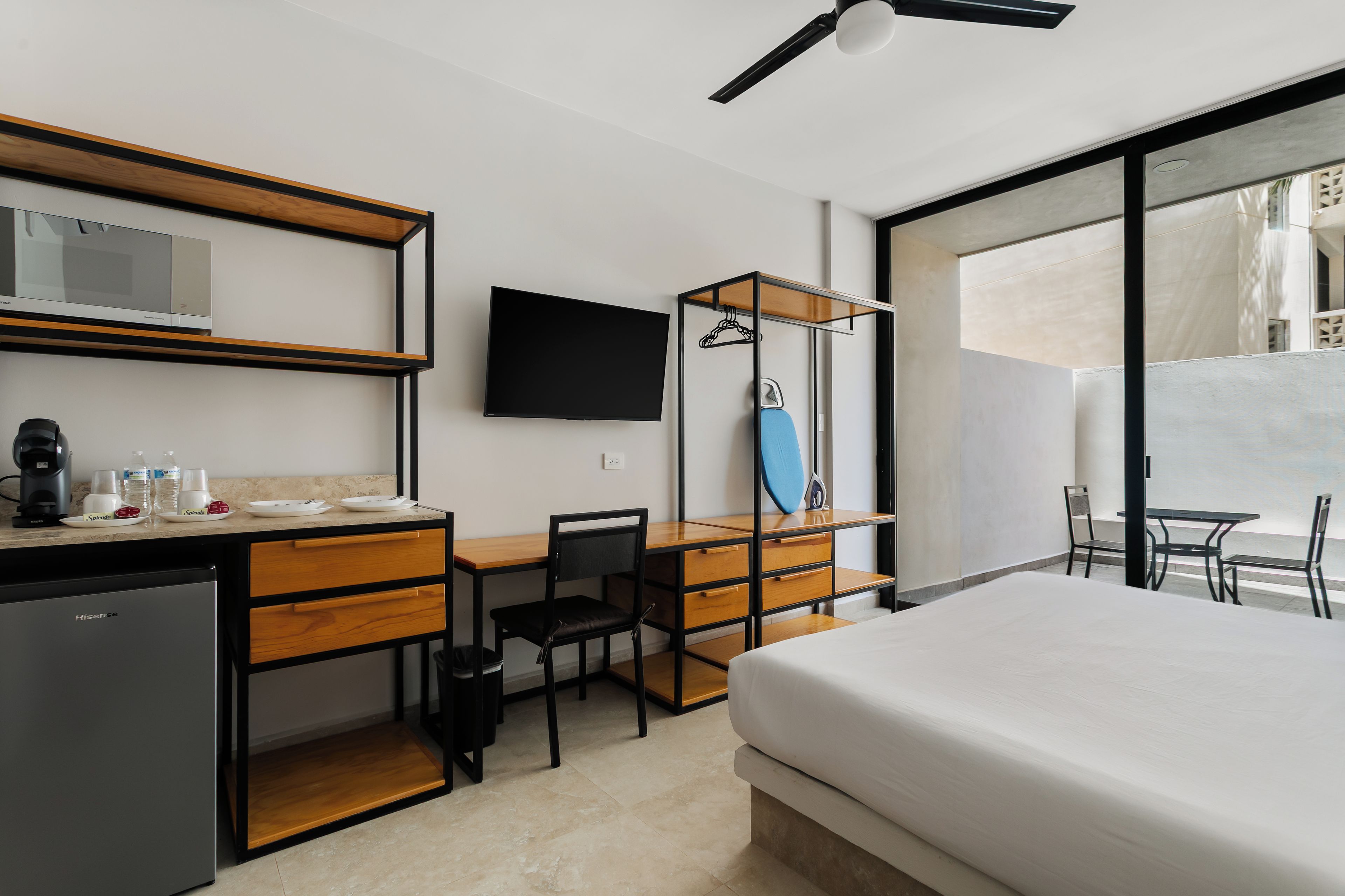 Camera d'albergo con letto, scrivania, sedia e televisore a schermo piatto montato a parete.