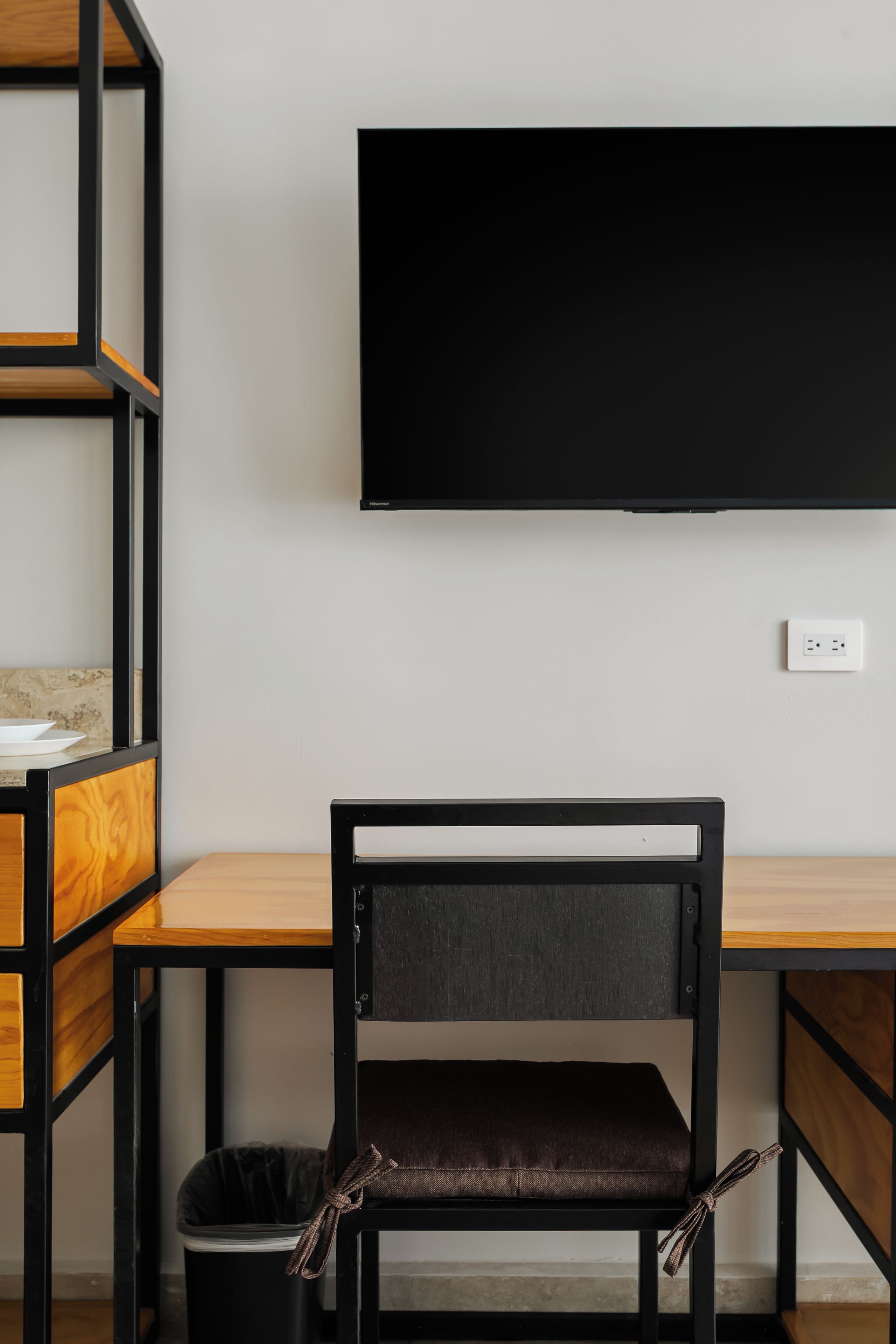 Un fauteuil de bureau moderne, doté d’un siège et d’un dossier rembourrés, placé devant un bureau avec une structure noire et un plateau en bois.