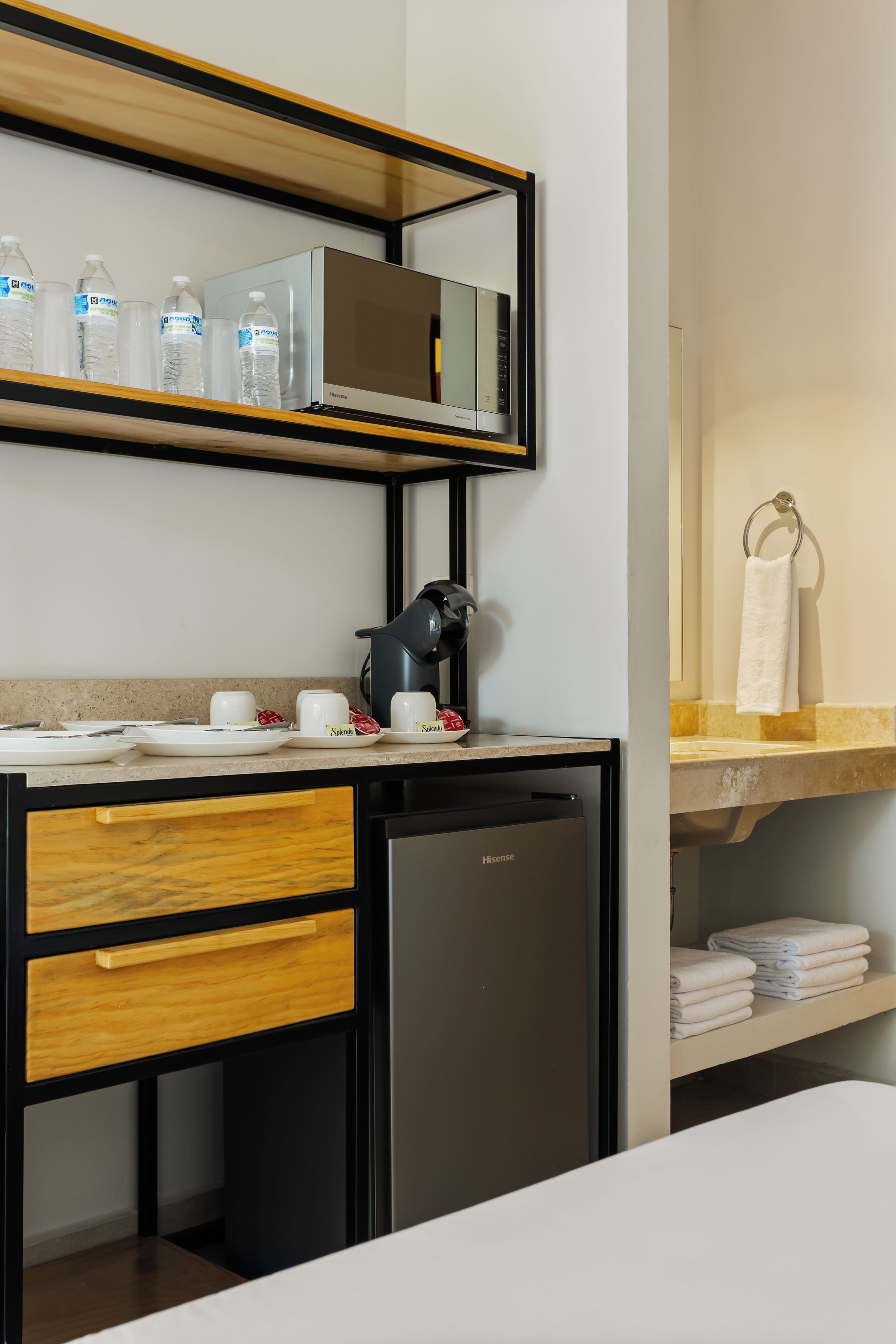A modern bathroom with a built-in sink, a mirror, a black coffee machine, and a towel rack.