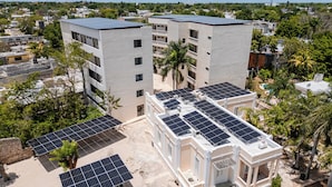 Un edificio de varios pisos con paneles solares en el techo y un pequeño jardín.