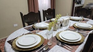 A dining table set with white plates, gold-rimmed cutlery, and a vase with flowers. - Casa Efra | Entire Home in Tela | A/C | 3BR | Sleeps 8 | Near Beach (Tela)