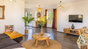 Ein Wohnzimmer mit einer Couch, einem Couchtisch, einem Fernseher und einem Essbereich mit Stühlen.