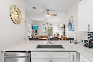 A kitchen with a built-in dishwasher, a large sink, and a ceiling fan. - Heron's Watch Way 3304 (Santa Rosa Beach)