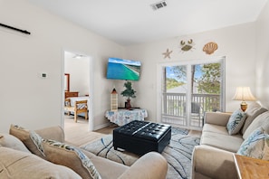 A living room with a television, a coffee table, and a sofa. - Heron's Watch Way 3304 (Santa Rosa Beach)