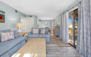 Ein Wohnzimmer mit Sofa, Couchtisch und Blick durch eine Glastür.