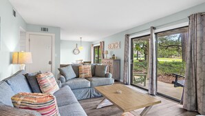 A living room with a sofa, a coffee table, and a view of the outdoors. - Seascape Golf Villas 10E (Miramar Beach)