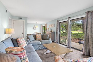 Ein Wohnzimmer mit einer Couch, einem Couchtisch und Blick ins Freie.