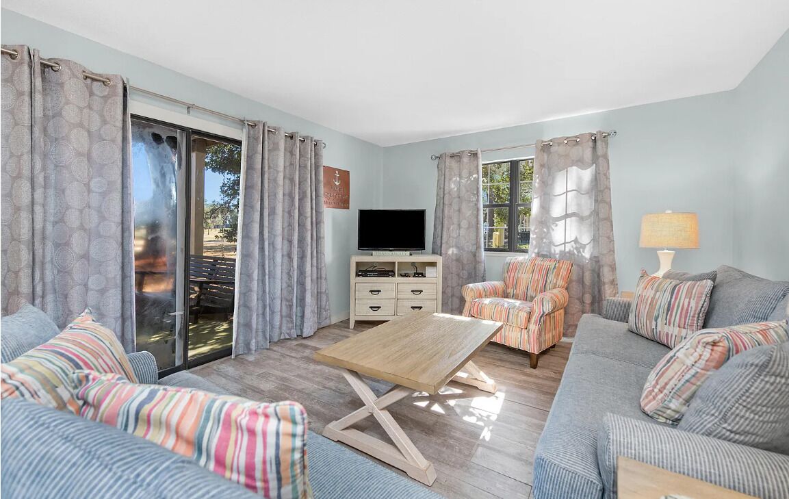 A living room with a sofa, armchair, TV, and a table.