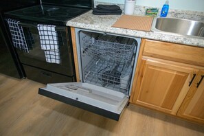 Une cuisine équipée d’un lave-vaisselle, d’un four et de meubles de rangement en bois.