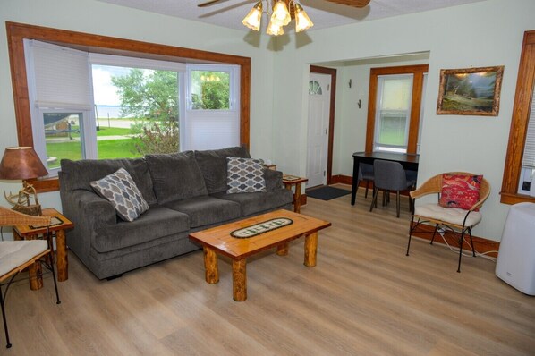 A living room with a sofa, coffee table, lamp, and a dining area with a chair and table.