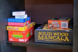 A shelf with various board games including Apples to Apples, Skipbo, and Solid Wood Mancala.