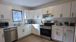 A kitchen with white cabinets, a dishwasher, an oven, and a microwave. - Updated Chimney Rock cabin - Views & River Sounds (Chimney Rock)
