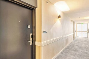 A hallway with a door, a wall-mounted light, and a doorbell. - High Rise 10th Floor City Views Free Pkg, Gym (Salt Lake City)