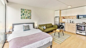 Ein modernes Hotelzimmer mit Bett, einer Couch, einer Waschmaschine, einer Mikrowelle und einem Herd.