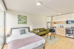 A modern hotel room with a bed, a sofa, a washing machine, a microwave, and a stove. - High Rise 10th Floor City Views Free Pkg, Gym (Salt Lake City)