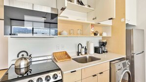 A modern kitchen with a stove, sink, and built-in appliances. - Mountain View 9th Floor City Views Free Pkg, Gym (Salt Lake City)