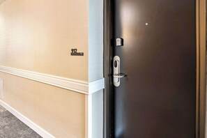 Una puerta con placa de número, manija y cerradura electrónica.