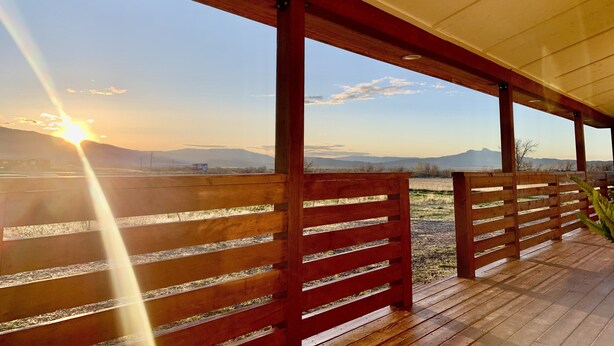Un espacio al aire libre cubierto con bancos de madera y vistas a montañas distantes.