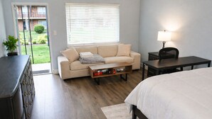 Un dormitorio con cama, sofá, mesa de centro, escritorio y lámpara.