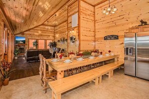 Ein Holzinterieur mit Esstisch für vier Personen, einer Couch und einer Küchenzeile mit Kühlschrank.