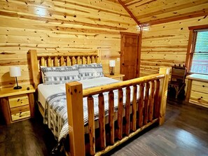L'intérieur d'une cabane en bois, avec un lit, des tables de chevet et une fenêtre.