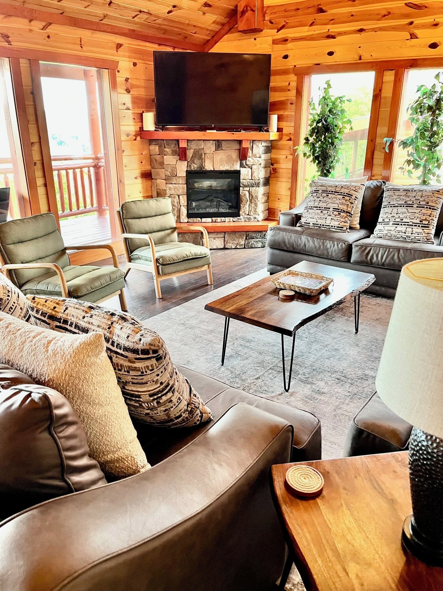 A cozy living room with a stone fireplace, leather sofas, and a flat-screen TV mounted above it.