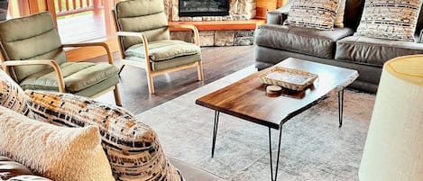 A cozy living room with a stone fireplace, leather sofas, and a flat-screen TV mounted above it.