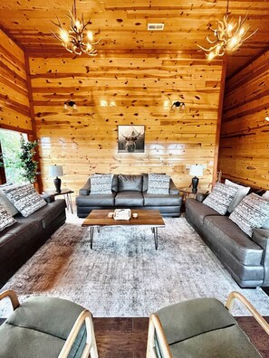A cozy cabin interior with a wooden ceiling, a sofa set, a coffee table, and a framed picture on the wall. - Luxury Lodge-Private Chef-Private Heated Pool-Amazing Views-Sleeps 24 (Sevierville)