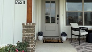 A white building with a brick column, a gray door, and a window.