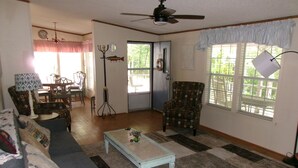Una sala de estar con sofá, sillón, mesa de centro y un comedor con sillas y una mesa.