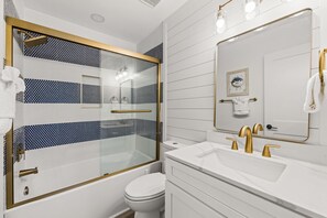 A modern bathroom with a glass-enclosed shower, a white sink with gold fixtures, and a large mirror. - Brand NEW Luxury Beachfront Paradise ~ Minutes to 30a! (Panama City Beach)
