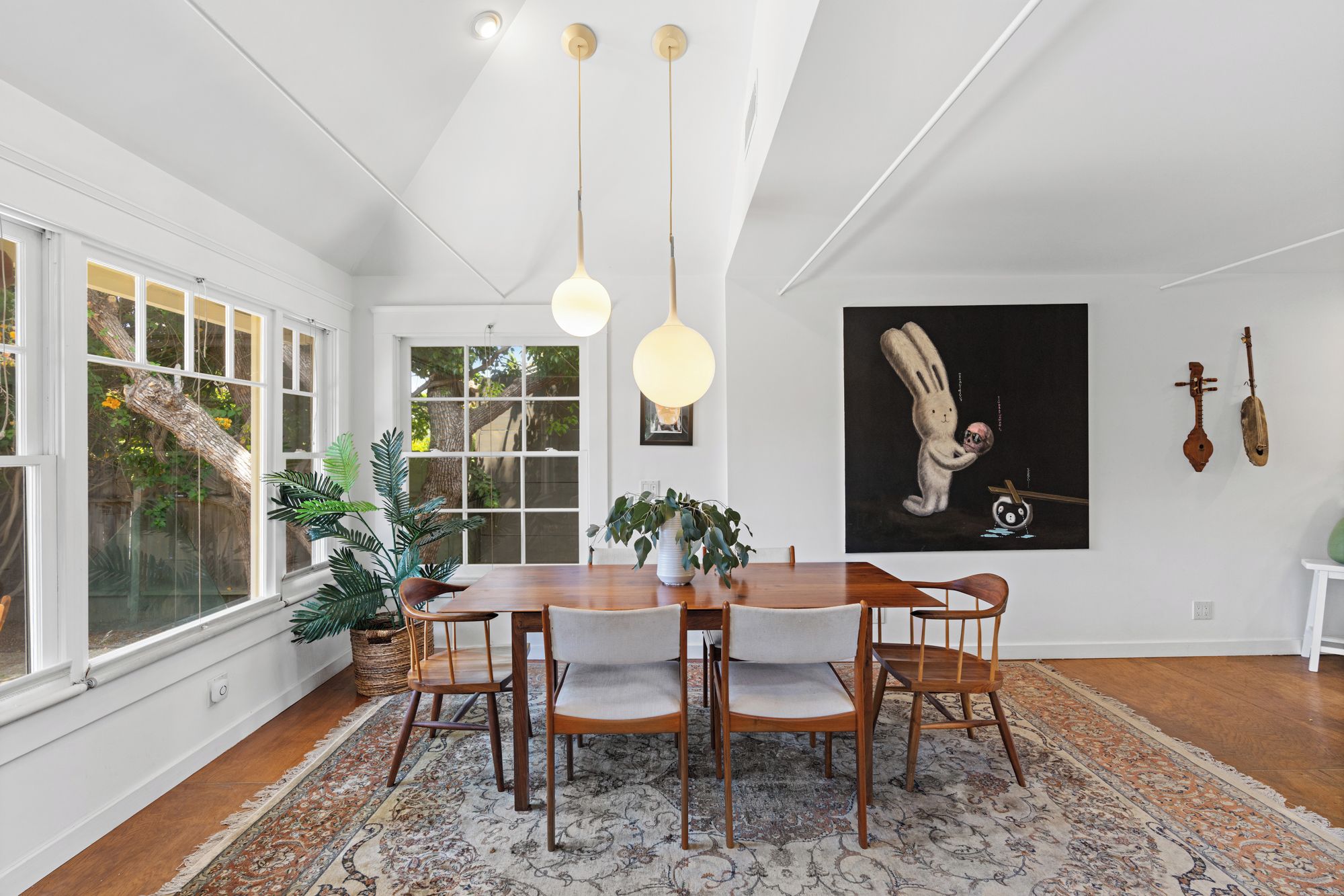 A dining area with a wooden table, chairs, and a patterned rug.