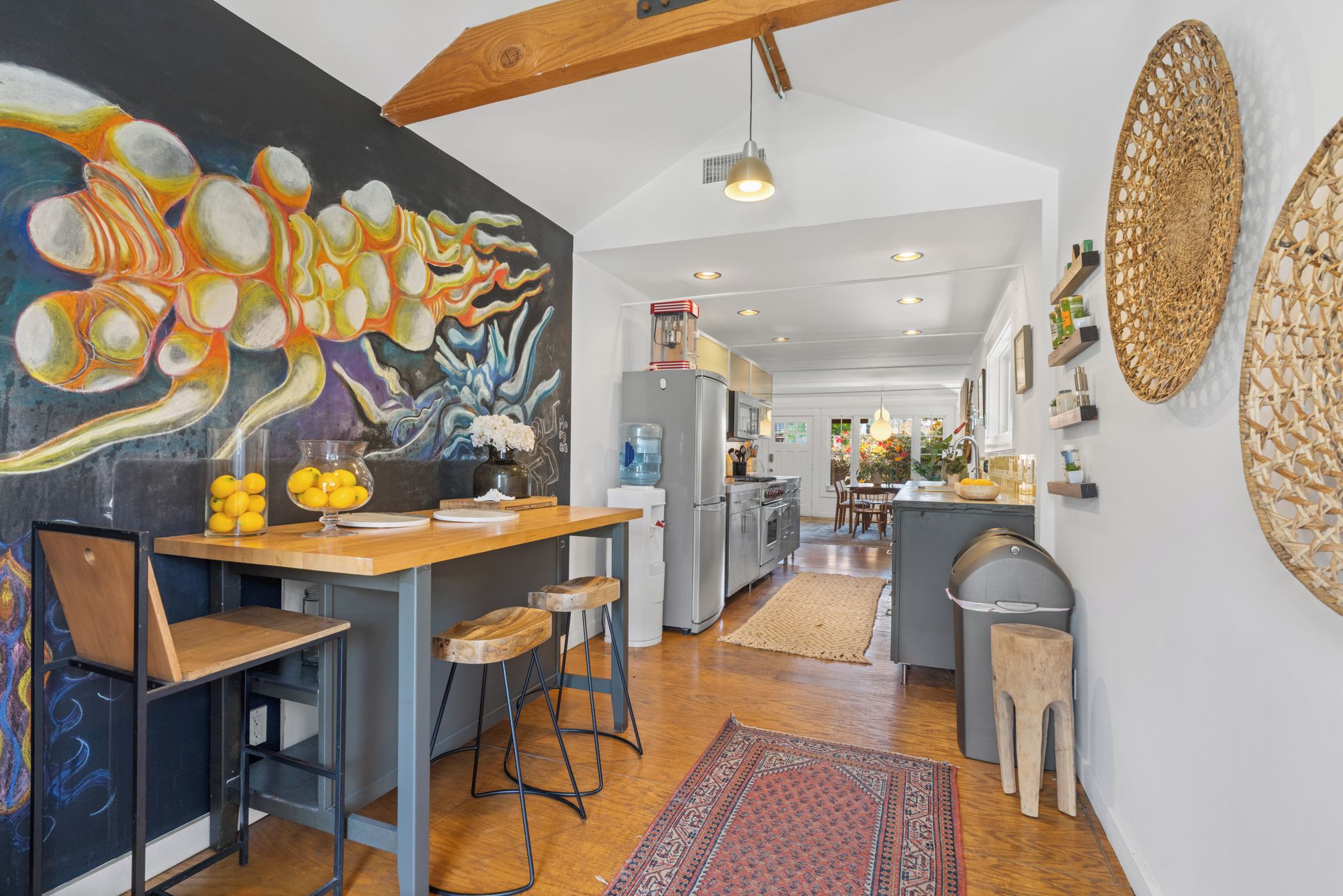 A modern kitchen with a central island, bar stools, and a vibrant abstract painting on the wall.