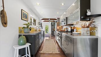A modern kitchen with stainless steel appliances, a central island, and a view into the dining area.