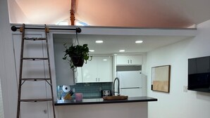 A modern kitchen with white cabinets, a wooden countertop, and a hanging plant. - Newly renovated, Stylish Studio Beach Bungalow a couple of blocks from the beach (Los Angeles)